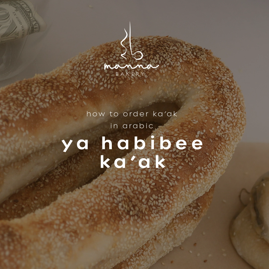 Sesame-covered ka’ak bread with text 'how to order ka’ak in Arabic ya habibee ka’ak' and Manna Bakery logo.